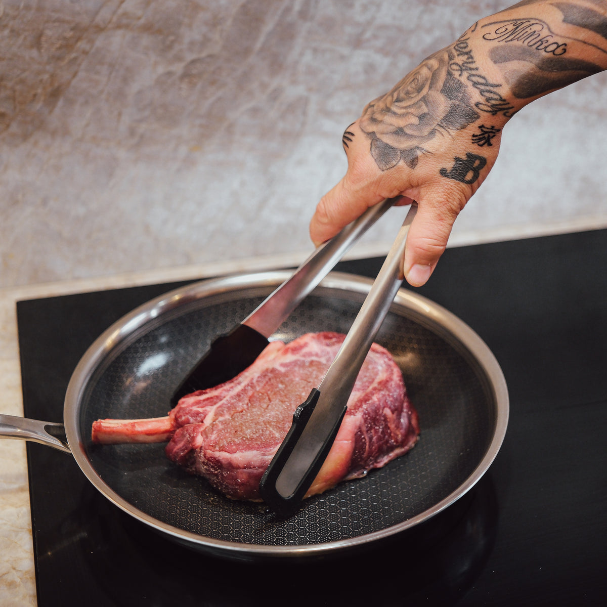 Keittiöpihdit kääntävät pihviä paistinpannussa