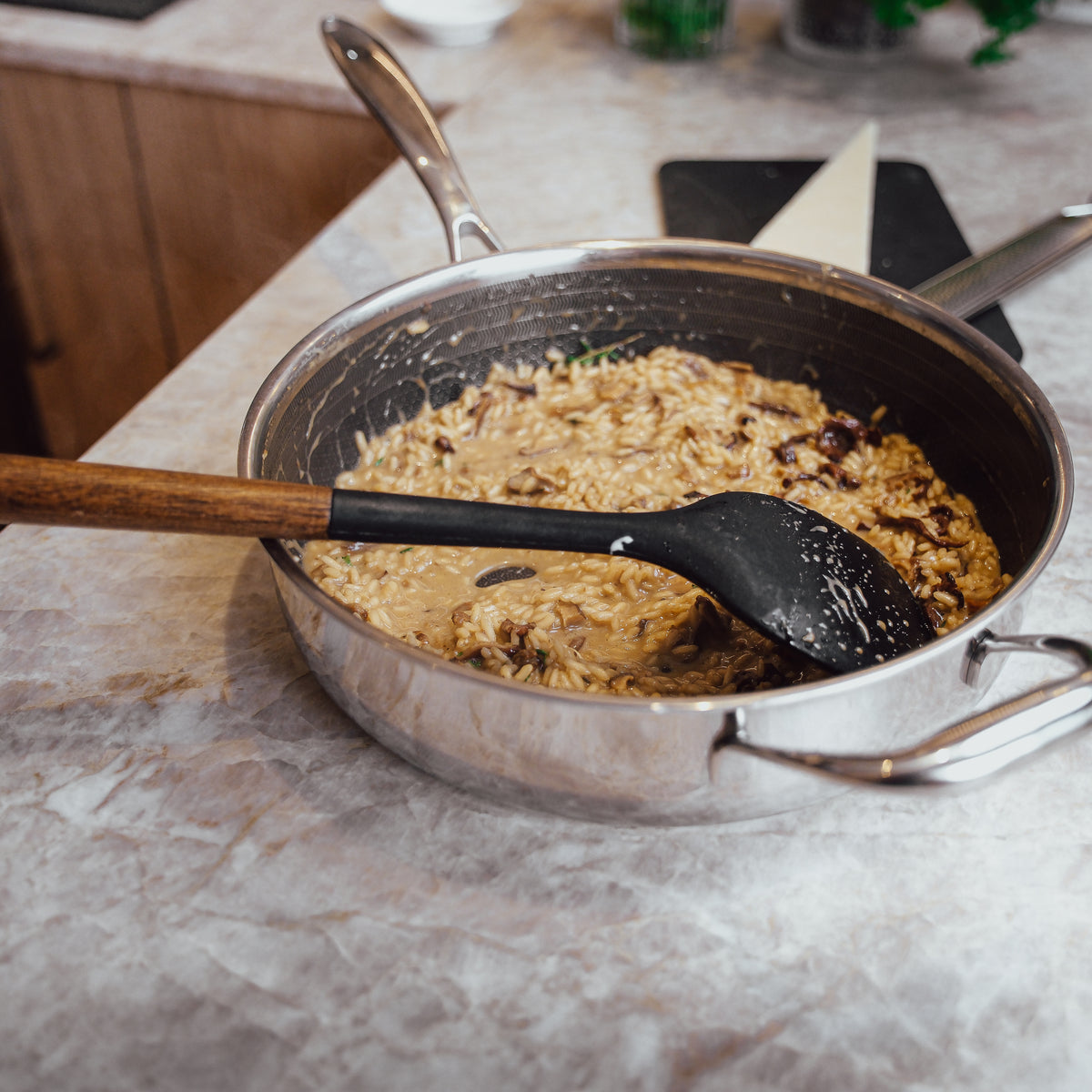 Keittiöväline sekoittaa risottoa sautépannussa